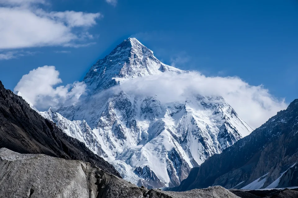 K2 rising above clouds and glacial terrain.